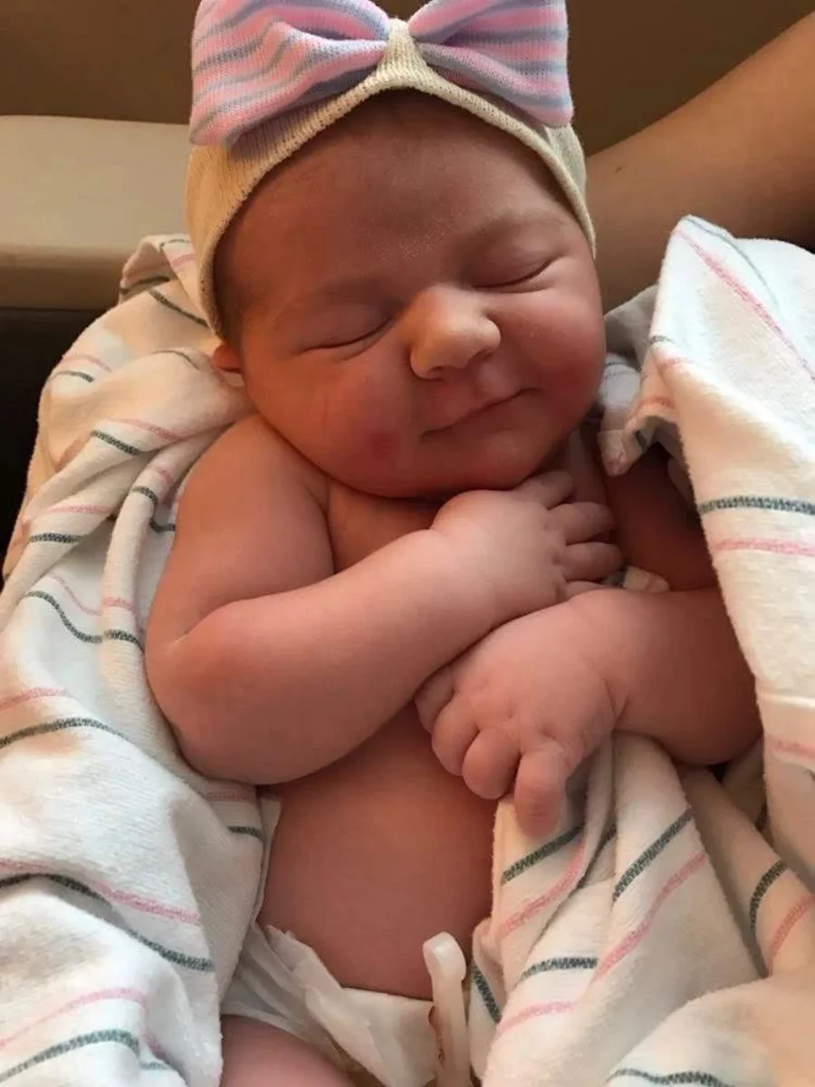 A swaddled newborn in a knitted hat, sleeping soundly